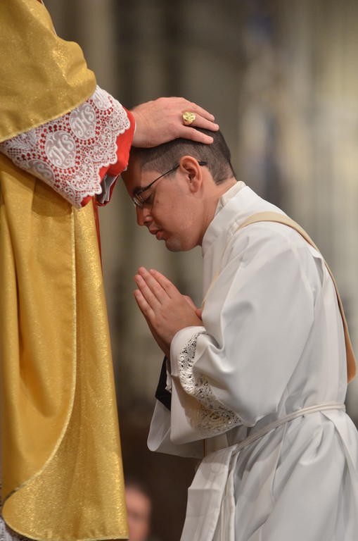 SYMBOLIC—In a key part of the ordination rite, Archbishop Dolan lays his hands on the head of Deacon Adaly Rosado, soon to become Father Rosado.