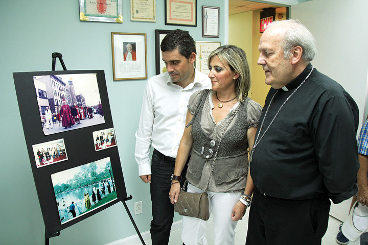 LEGADO—El Obispo Iriondo, mira un arreglo de fotos, incluyendo una del Obispo Garmendia con la Madre Teresa y el sobrino del fallecido obispo, Néstor Garmendia y su esposa Maria.