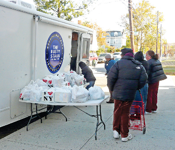HOPE ON WHEELS—People line up to receive bags of food donations last week from the Rusty Staub Foundation truck parked outside the CYO Staten Island Center on Anderson Avenue. The former Mets star has been a long-time partner of archdiocesan Catholic Charities in fighting hunger.