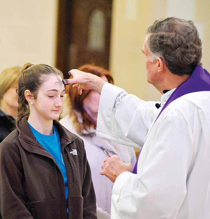 FAITH—Students of Resurrection School in Rye receive ashes from Msgr. Donald Dwyer, pastor of Resurrection parish, on Ash Wednesday last year. Learning about and receiving the sacraments are integral parts of a Catholic school education.