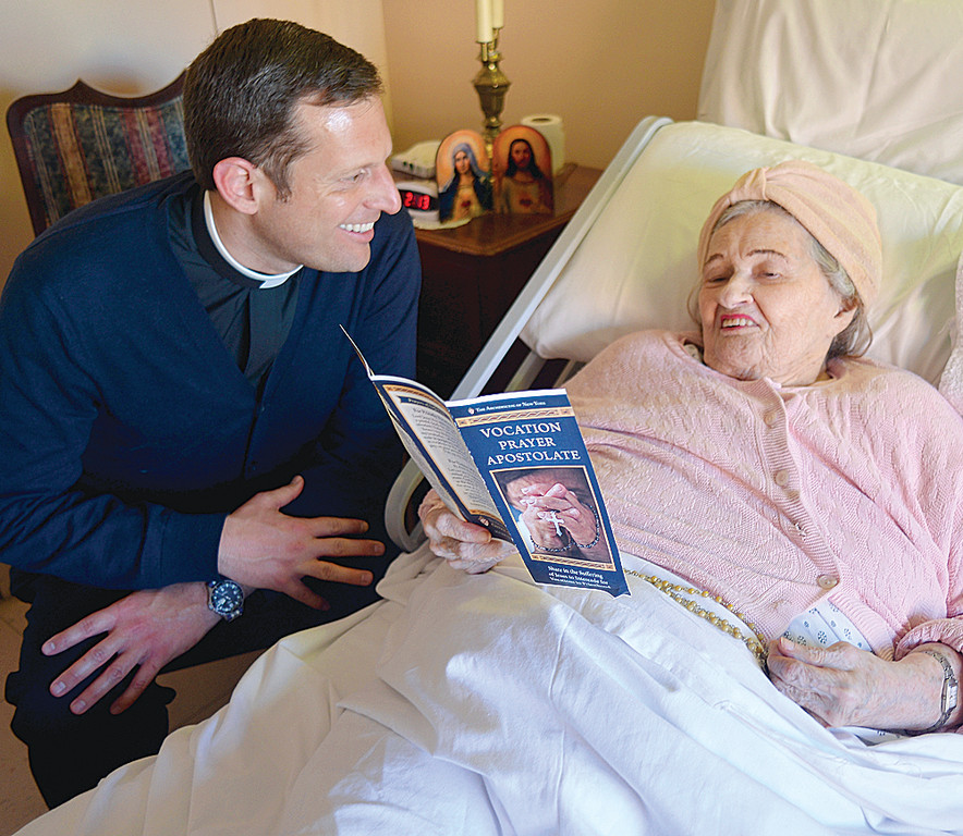 OFFERING IT UP—Father Enrique Salvo, director of the archdiocesan Office of Vocations, visits with Kathleen Gannon in her room at Amsterdam House in the Morningside Heights section of Manhattan. She is among the homebound participating in the archdiocese’s Vocation Prayer Apostolate to increase vocations to the priesthood. Father Salvo is a priest in residence at nearby Notre Dame parish.