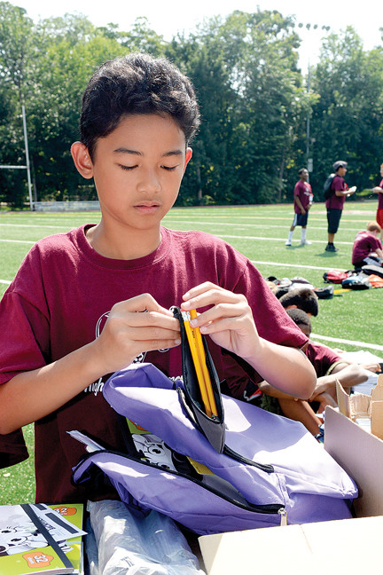 Scott Castillo, a student in the Fordham Preparatory School Higher Achievement Program, fills a backpack with school supplies for prekindergarteners and kindegarteners in need for the program “Operation Backpack” on the Bronx school’s track July 29.