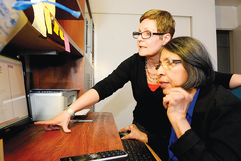 Marlyn Alvarez, standing, teaches Jane Hidalgo how to do research on the computer earlier this month as part of her volunteer service with ArchCare’s TimeBank.