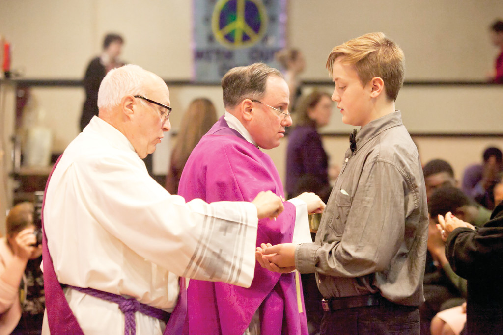 Teens receive Communion from Deacon Angelo Corsaro of Sacred Heart parish in Monroe and Father Martine.