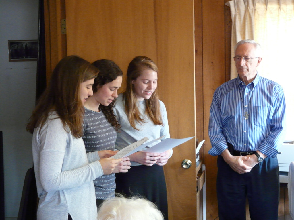 LAMP missionaries Samantha Chestney, Hailey Megge and Sarah Mutchler participate in a ceremony at Mass on Nov. 28 in which they each received a LAMP mission crucifix. At right is Tom Scheuring, co-director of LAMP Catholic Ministries.
