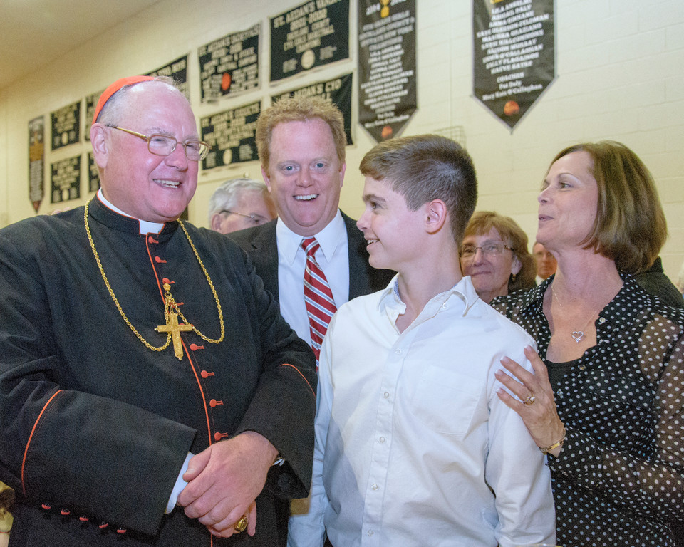 Cardinal Dolan greets Richard and Patricia Lenihan with their son Patrick, an altar server.