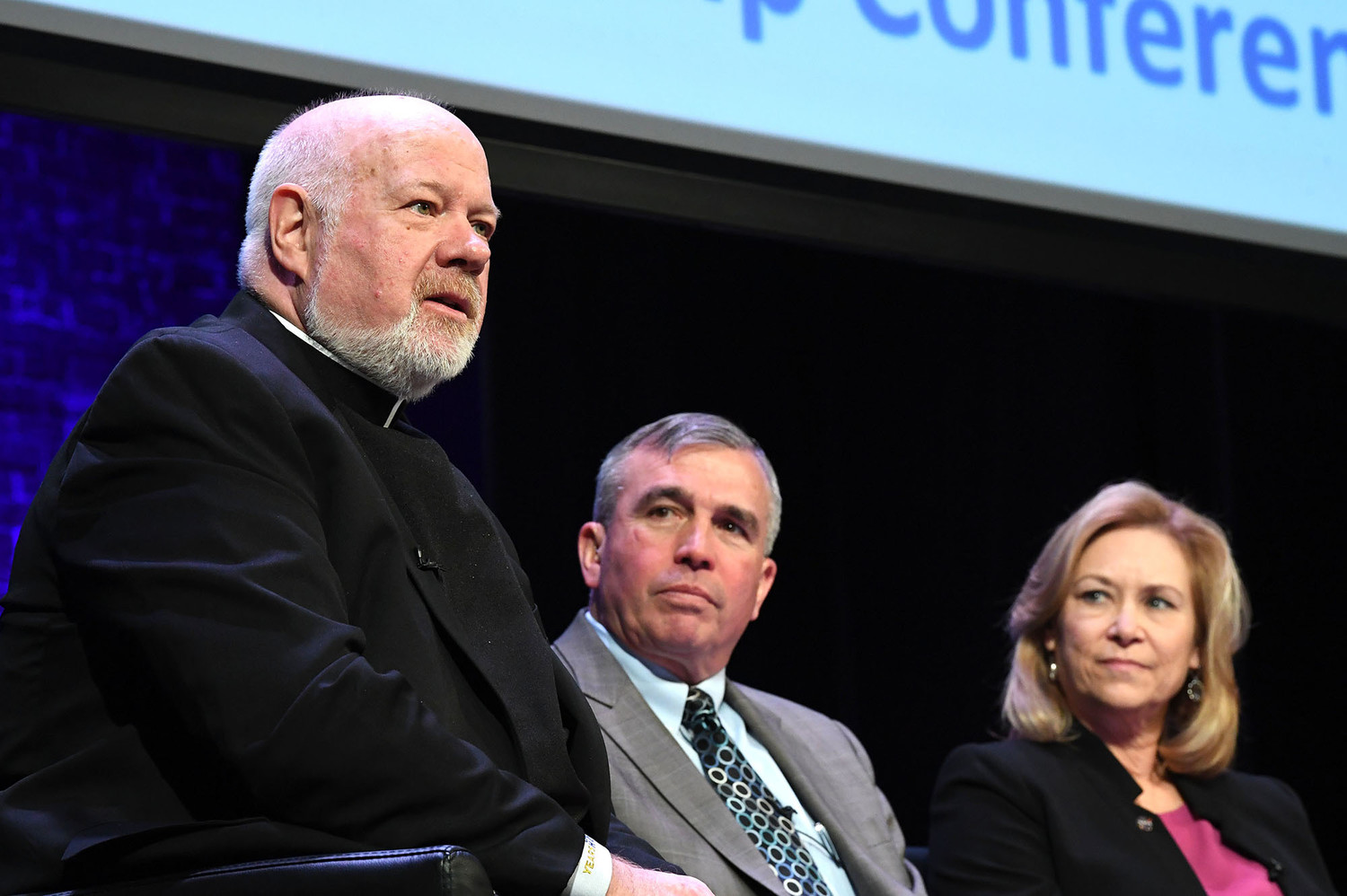 Msgr. Kevin Sullivan, executive director of archdiocesan Catholic Charities, speaks as retired U.S. Marine Corps Lieutenant General John Wissler and Janet Petro, deputy director of NASA’s John F. Kennedy Space Center in Florida, listen to their fellow panelist.