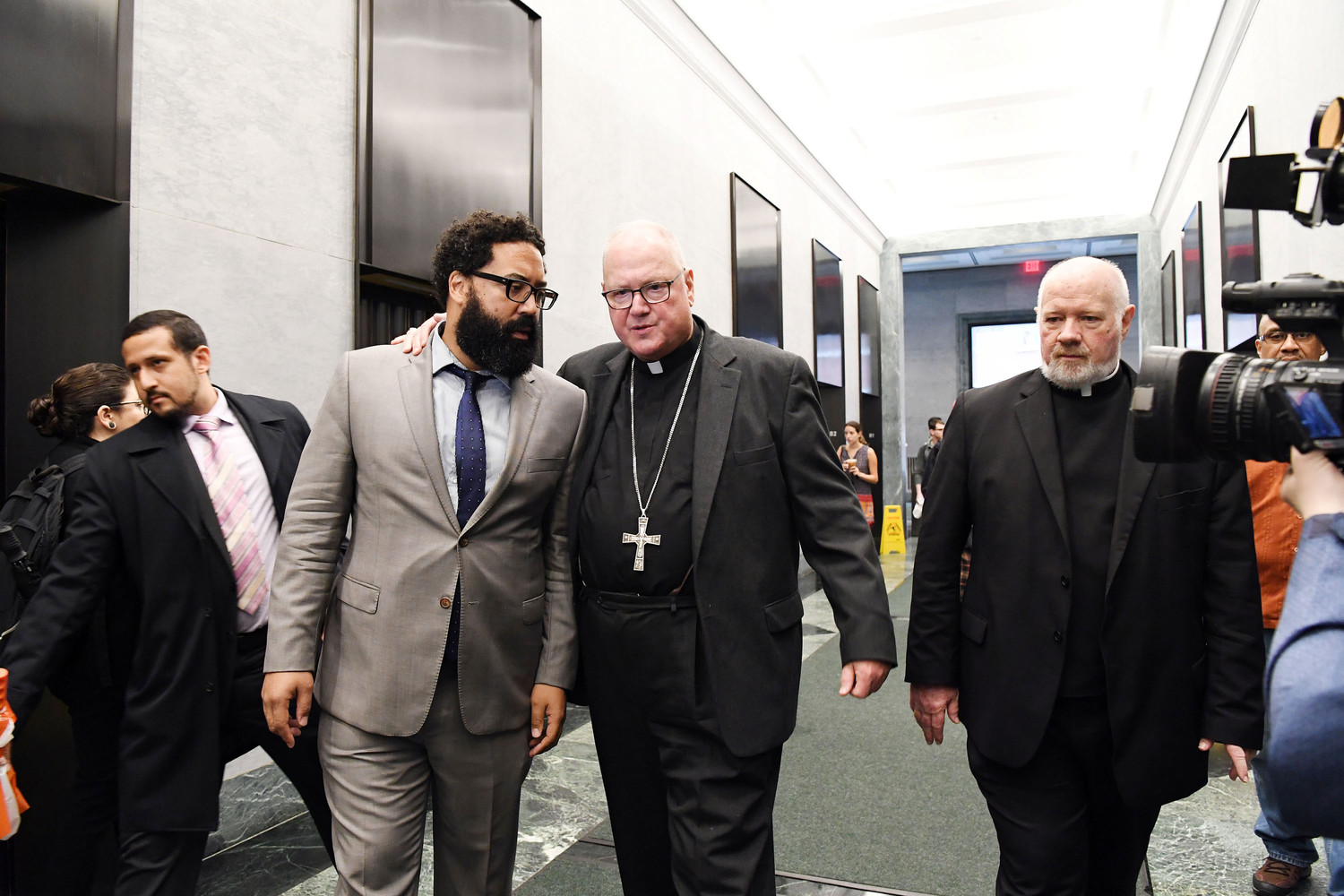Walking to the elevators at archdiocesan Catholic Charities Immigration Services in lower Manhattan June 28, Cardinal Dolan speaks with Marco Carrion of the Mayor’s staff. Msgr. Kevin Sullivan, executive director of Catholic Charities, is at right.