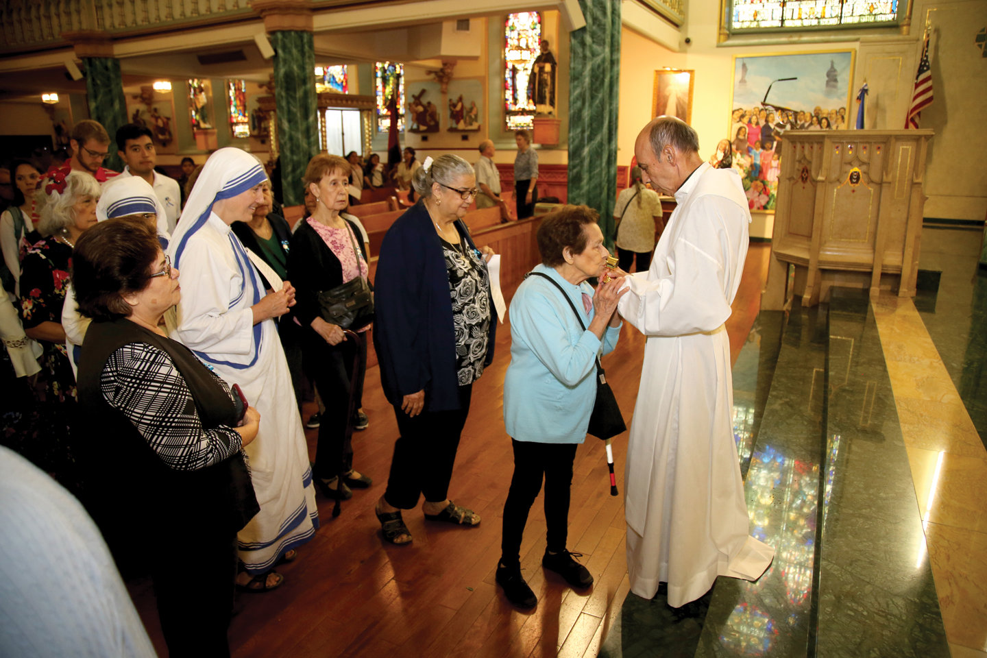 The parish pastor, Father Santiago Rubio, holds an encased relic of St. Teresa as congregants line up for veneration after the morning liturgy.