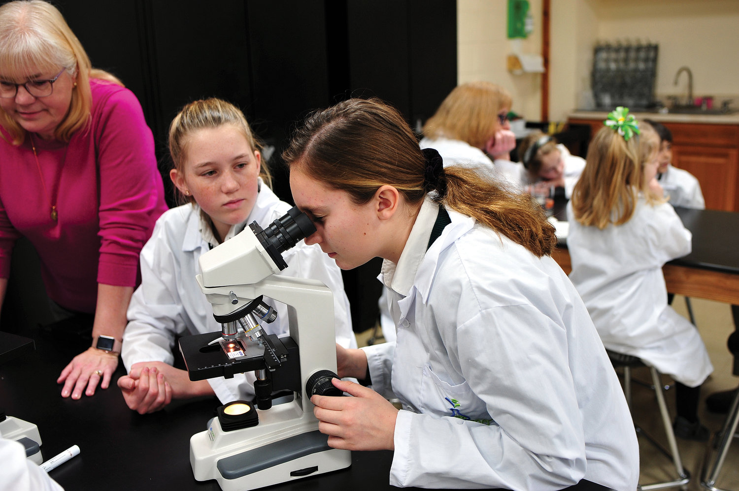 Deidre Connolly, left, and Jillian Beresford, students at St. Denis-St. Columba School in Hopewell Junction, use a microscope as science teacher Diana Spera looks on Jan. 10.