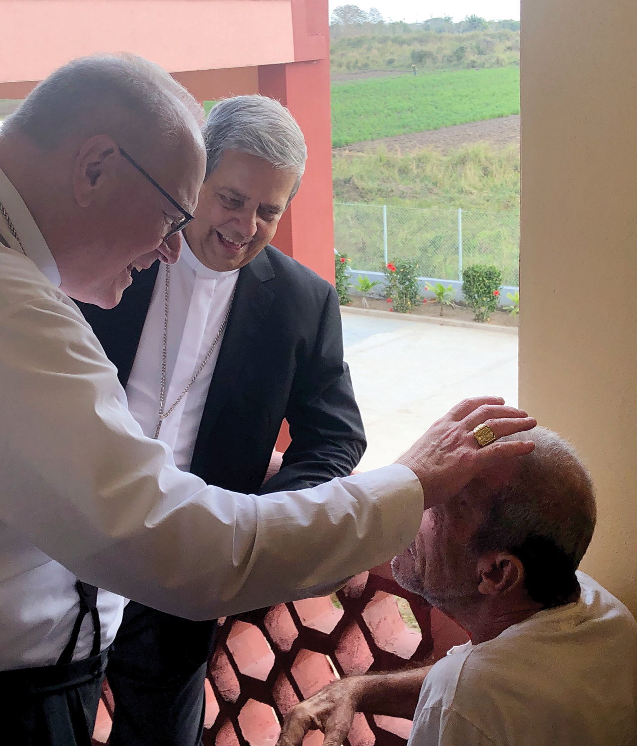 BENDICIÓN EN CUBA—El cardenal Dolan, acompañado por el arzobispo Wilfredo Pino Estévez de Cuba, traza la señal de la cruz en la frente de un hombre que vive en un hogar para ancianos en Camaguey, Cuba.