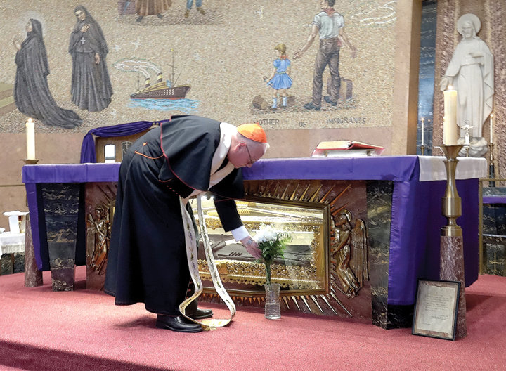 INTERCESIÓN—El cardenal Dolan, coloca flores en el santuario de Santa Frances Cabrini en Manhattan el 22 de marzo después de orar en privado por la curación y protección en la pandemia del coronavirus.