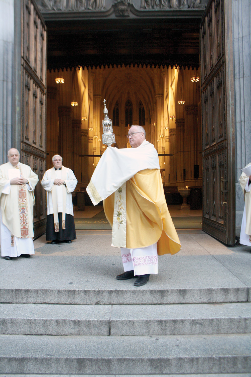 Cardinal Dolan, from the steps of the cathedral facing Fifth Avenue, blesses New York City with the Blessed Sacrament on Holy Thursday, April 9.
