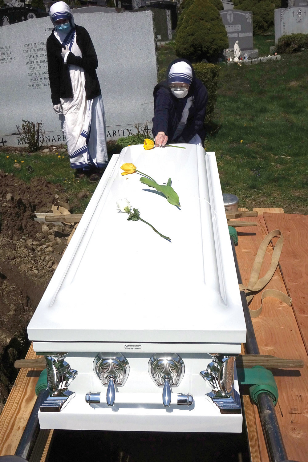 A Missionaries of Charity sister tenderly places a a flower on the casket of one of two deceased nuns, Sister Francesca. M.C., and Sister Gertrude, M.C., who were buried at Gate of Heaven Cemetery in Hawthorne April 25.