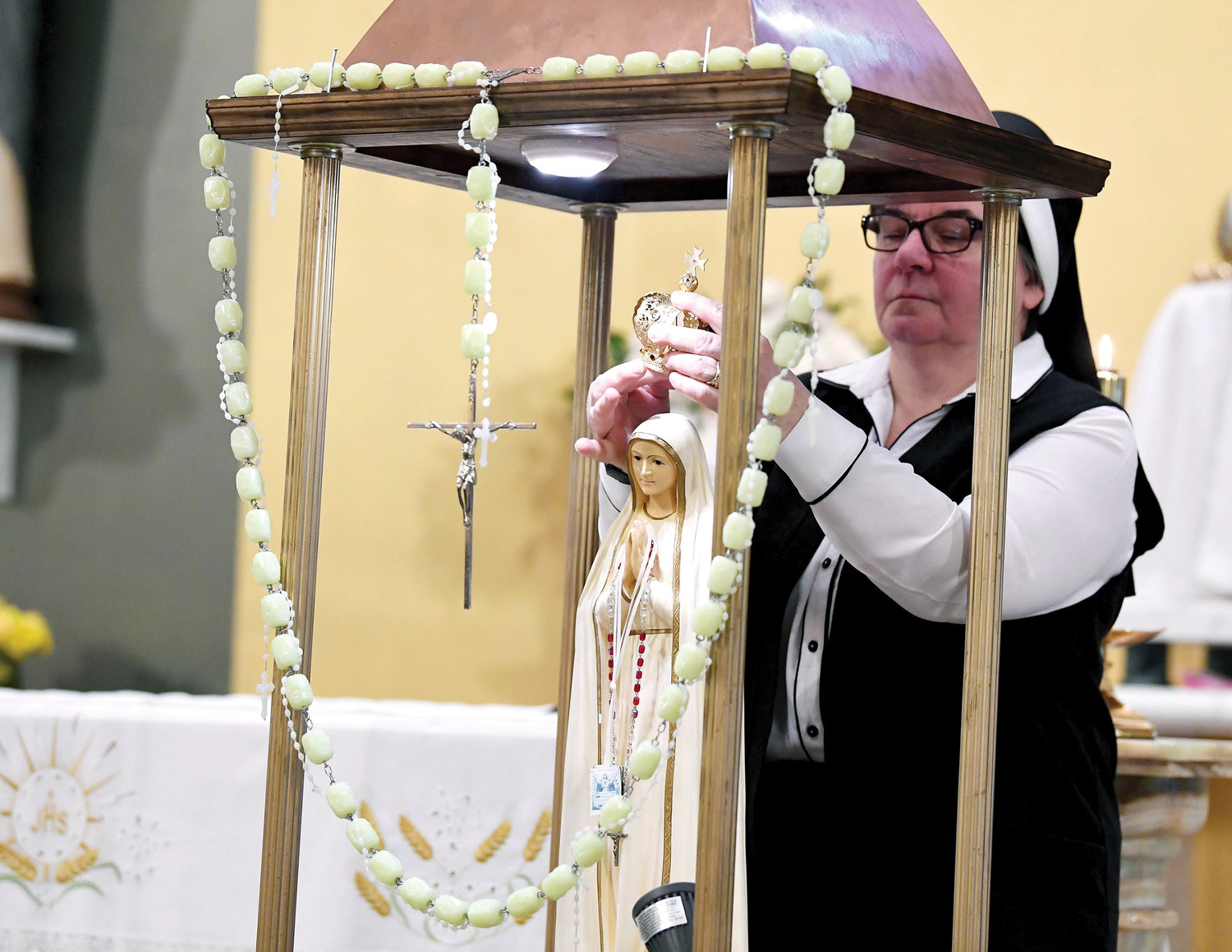 Sister Antonia Zuffante, C.S.JB., crowns a figure of Our Lady of Fatima on her feast day, May 13, in the sanctuary of Our Lady Help of Christians Church on Staten Island. Father Jeffrey Pomeisl, chaplain at Msgr. Farrell High School, led a Rosary rally involving a number of Staten Island Catholic school educators including Sister Antonia, who chairs the religion department at Msgr. Farrell. The rally, #MillionRosaryMay13th, drew many viewers to Father Pomeisl’s YouTube “Pomcast.”