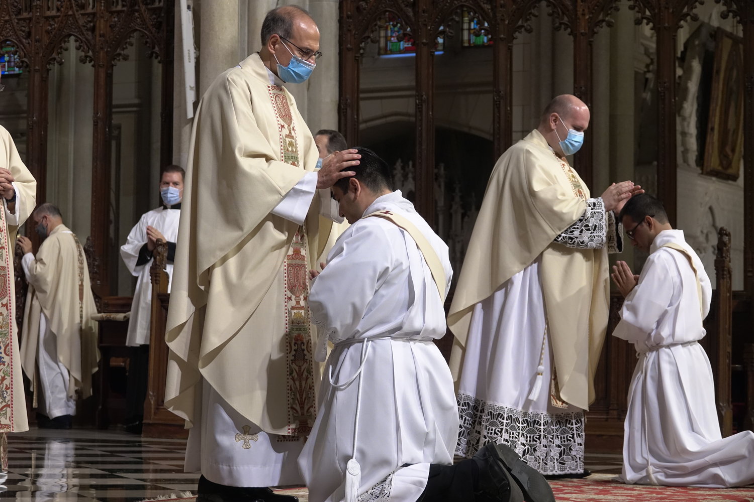Priests lay hands on the heads of their new priestly brothers.