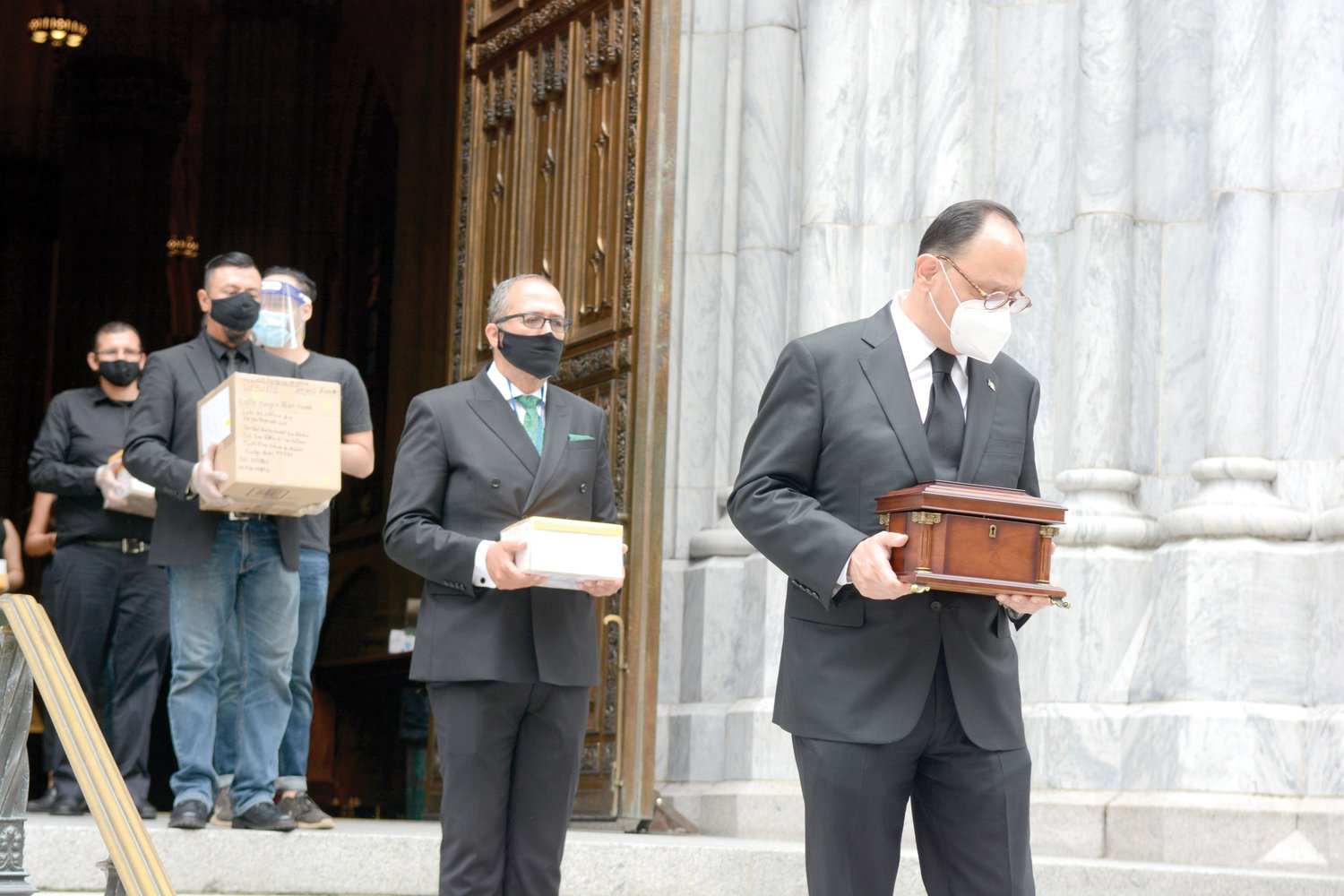 Jorge Islas Lopez, consul general of Mexico in New York, carries a box with the cremated remains of a coronavirus victim, as others follow him down the steps of St. Patrick’s Cathedral. They were leaving the cathedral after the July 11 prayer service for 250 Mexican-born Covid-19 victims who resided in the New York area.