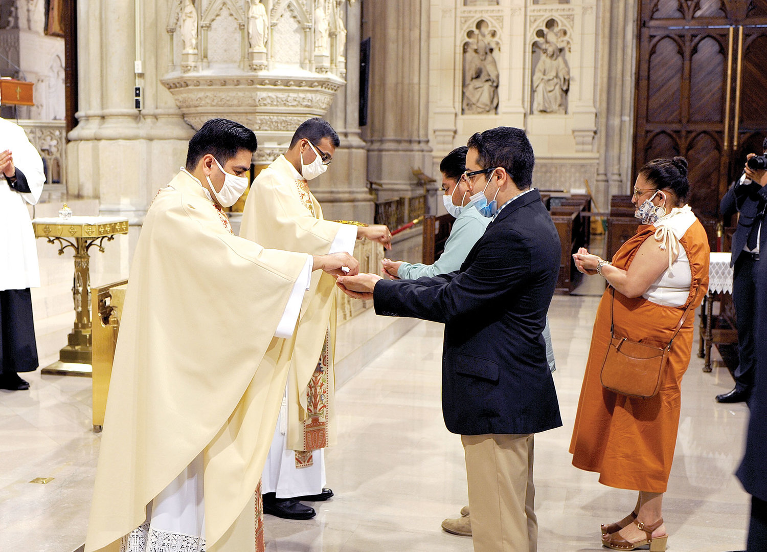 The two new priests distribute Holy Communion.