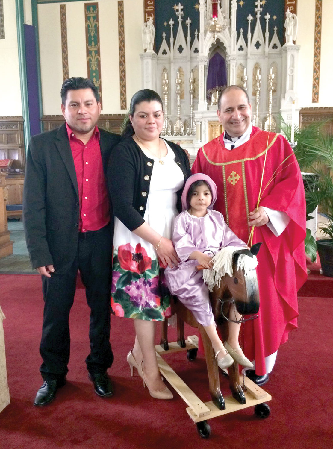 IN CHURCH—Father Pichardo greets parishioners Freddy and Veronica Baide and their daughter Katie after a Mass last December at St. Mary-St. Peter parish in Kingston.