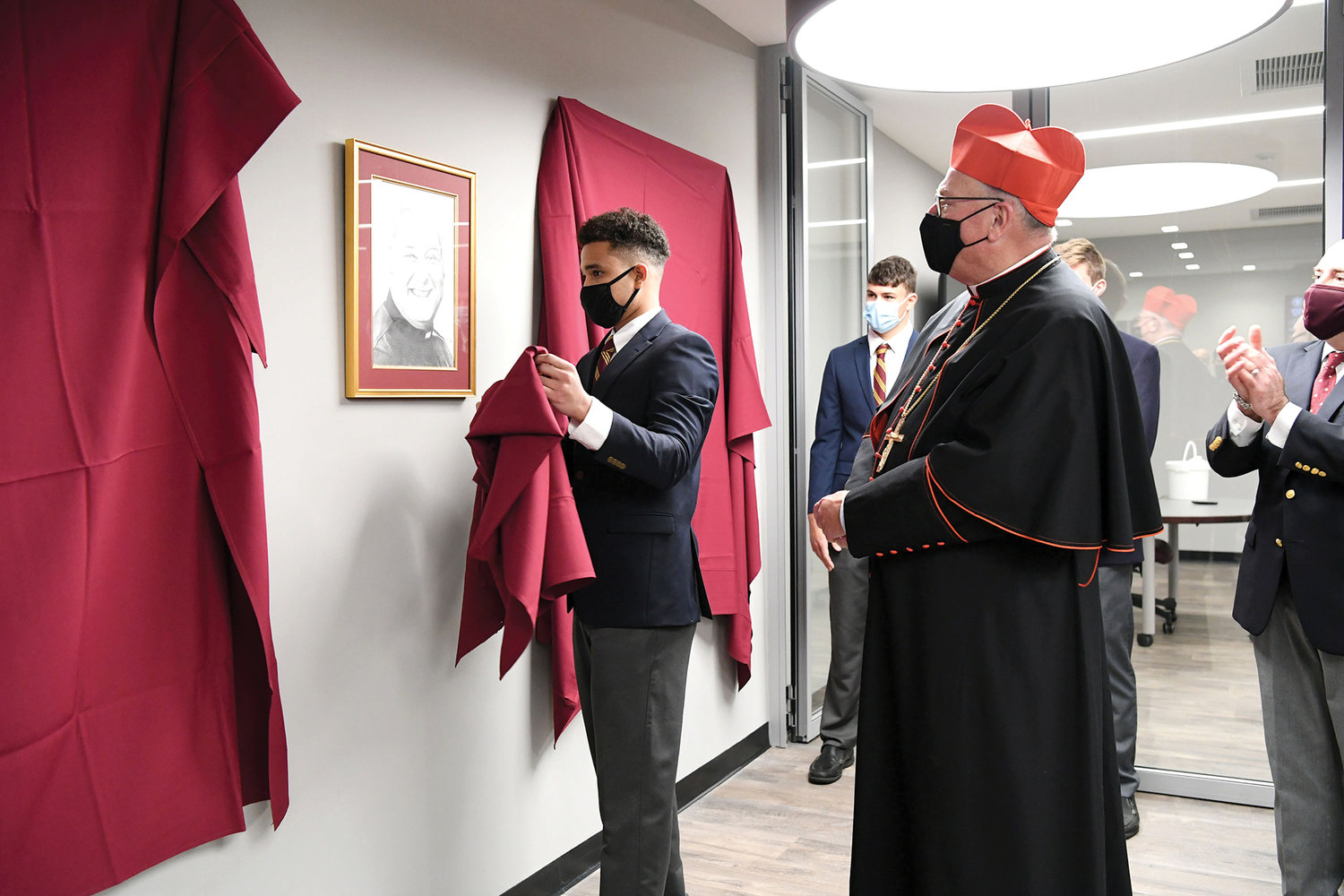 Msgr. Farrell High School student artist Christopher Jefairjian unveils his pencil drawing of Brother Henry S. Wright, C.F.C., during Cardinal Dolan’s visit to the Staten Island high school Oct. 28 to dedicate new campus facilities, including the Brother Henry S. Wright Learning Center. Brother Wright, who died Oct. 29, 2017, taught at Msgr. Farrell for 43 years.