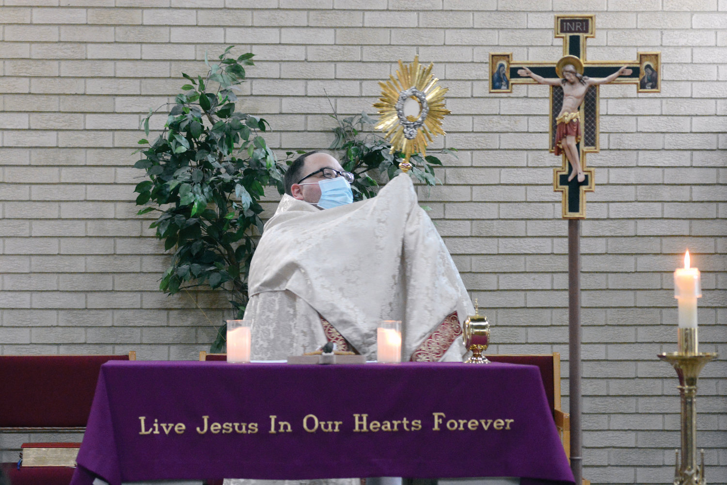 Father Cinnante elevates the monstrance holding the Eucharist.