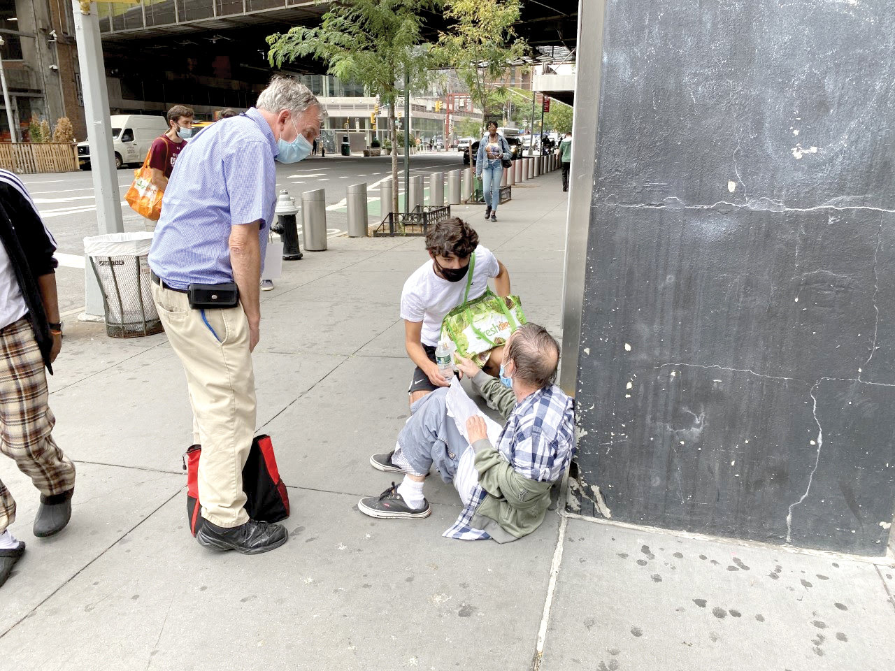 Ed Greene, left, co-pastoral director of LAMP, and NYU freshman Luis Gonzalez provide assistance to a man in Manhattan.