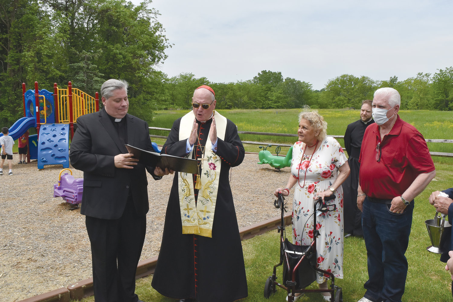 Cardinal Dolan blesses the playground for youngsters in the Faith First Early Childhood Program at St. Columba’s parish in Chester May 22. At far left is Father John Bonnici, pastor of St. Columba’s. At far back is Father Stephen Ries, the cardinal’s priest secretary.