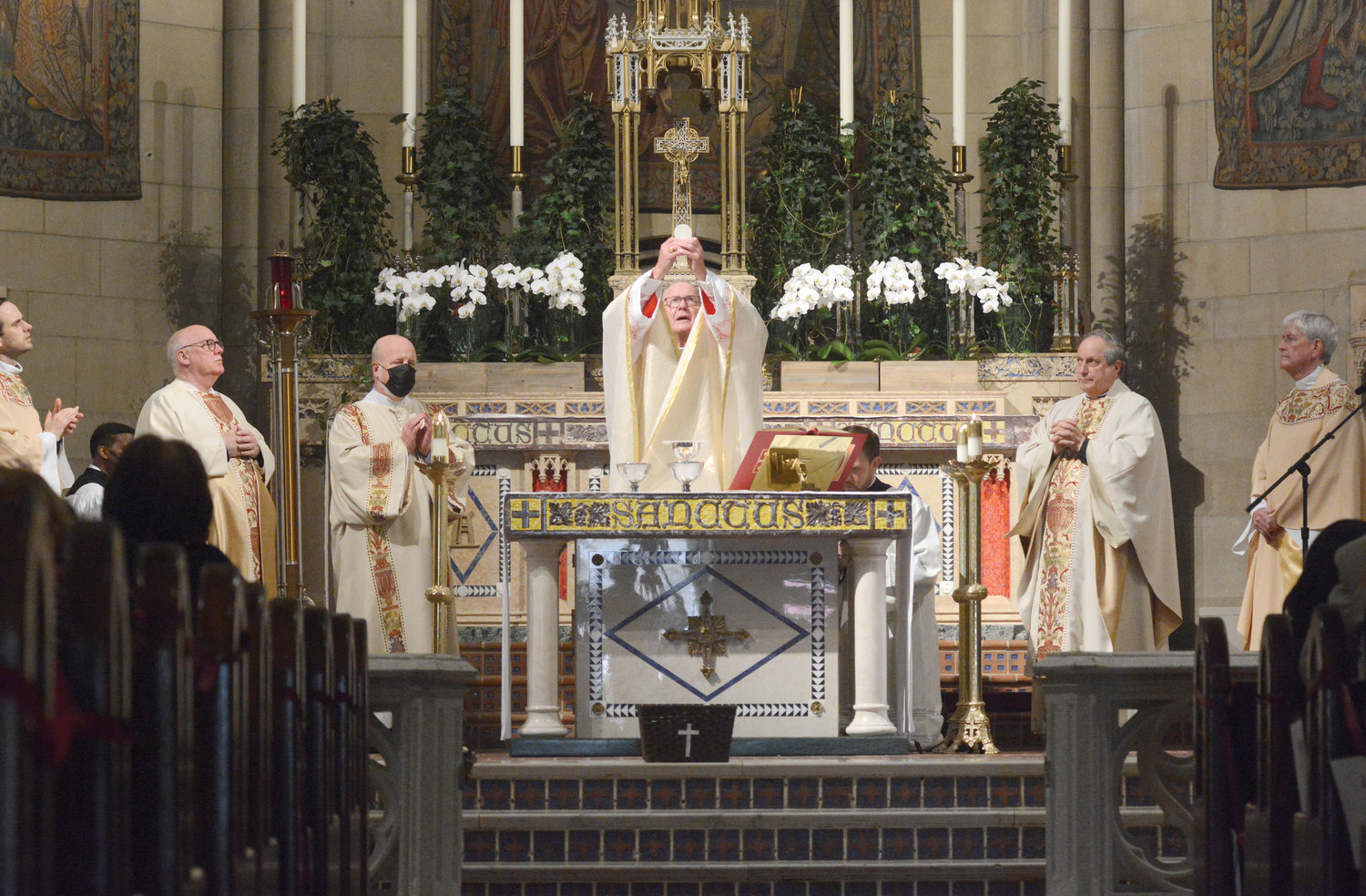 Cardinal Dolan elevates the Eucharist at  Mass marking the 100th anniversary of Blessed Sacrament Church in Manhattan June 20. Standing at the altar, from left, are Father Łukasz Dutkiewicz, parochial vicar; Father David Nolan, pastor; Deacon Scott Reisinger; Cardinal Dolan; Msgr. Thomas P. Sandi, pastor of Holy Trinity in Manhattan and regional dean; and Msgr. Michael Crimmins, in residence.