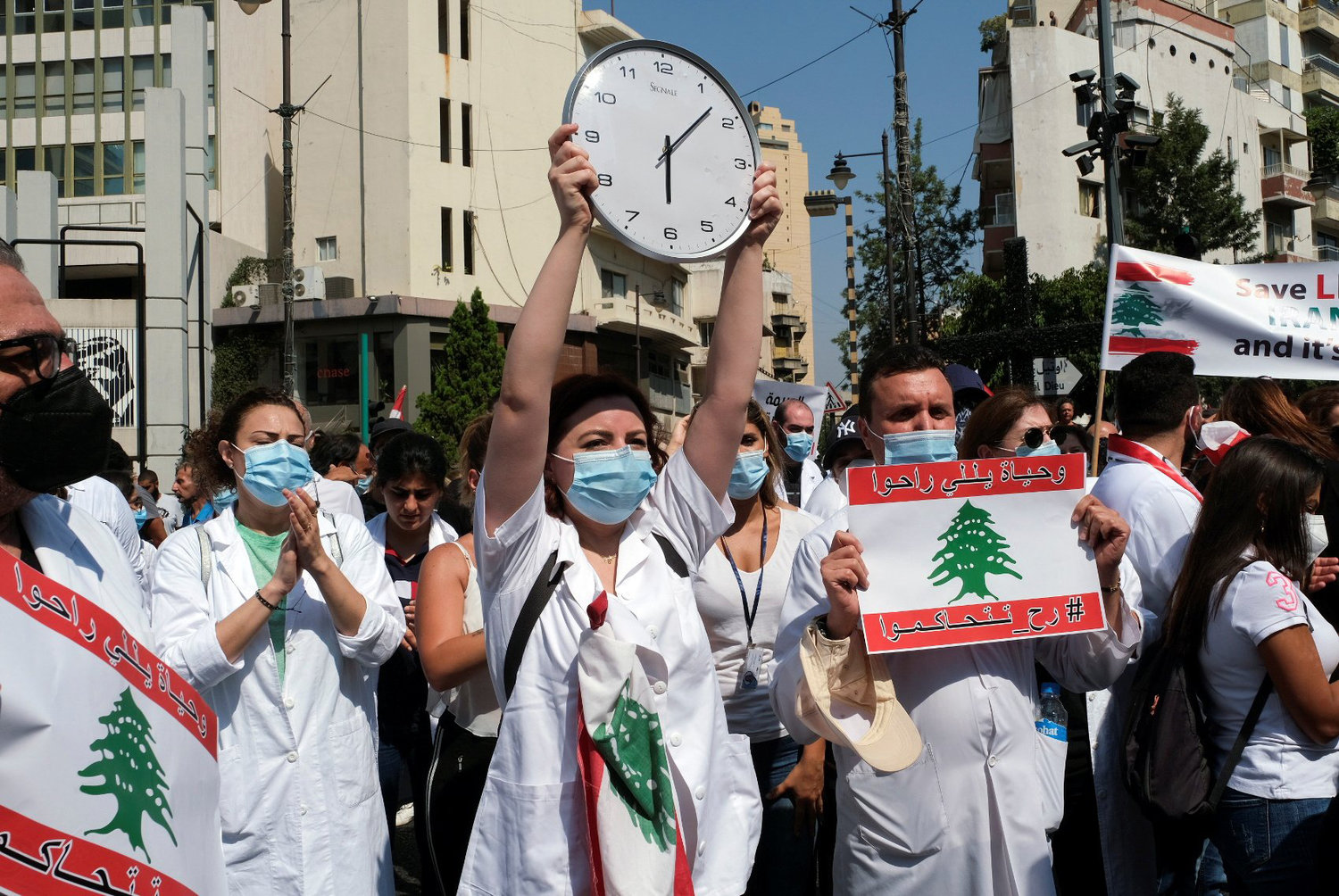 HOSPITAL REMEMBRANCE—Top, health care workers march outside St. George Hospital University Medical Center in Beirut Aug. 4, as they carry national flags and a clock showing the time of last year's Beirut port blast, as Lebanon marks the one-year anniversary of the massive explosion.