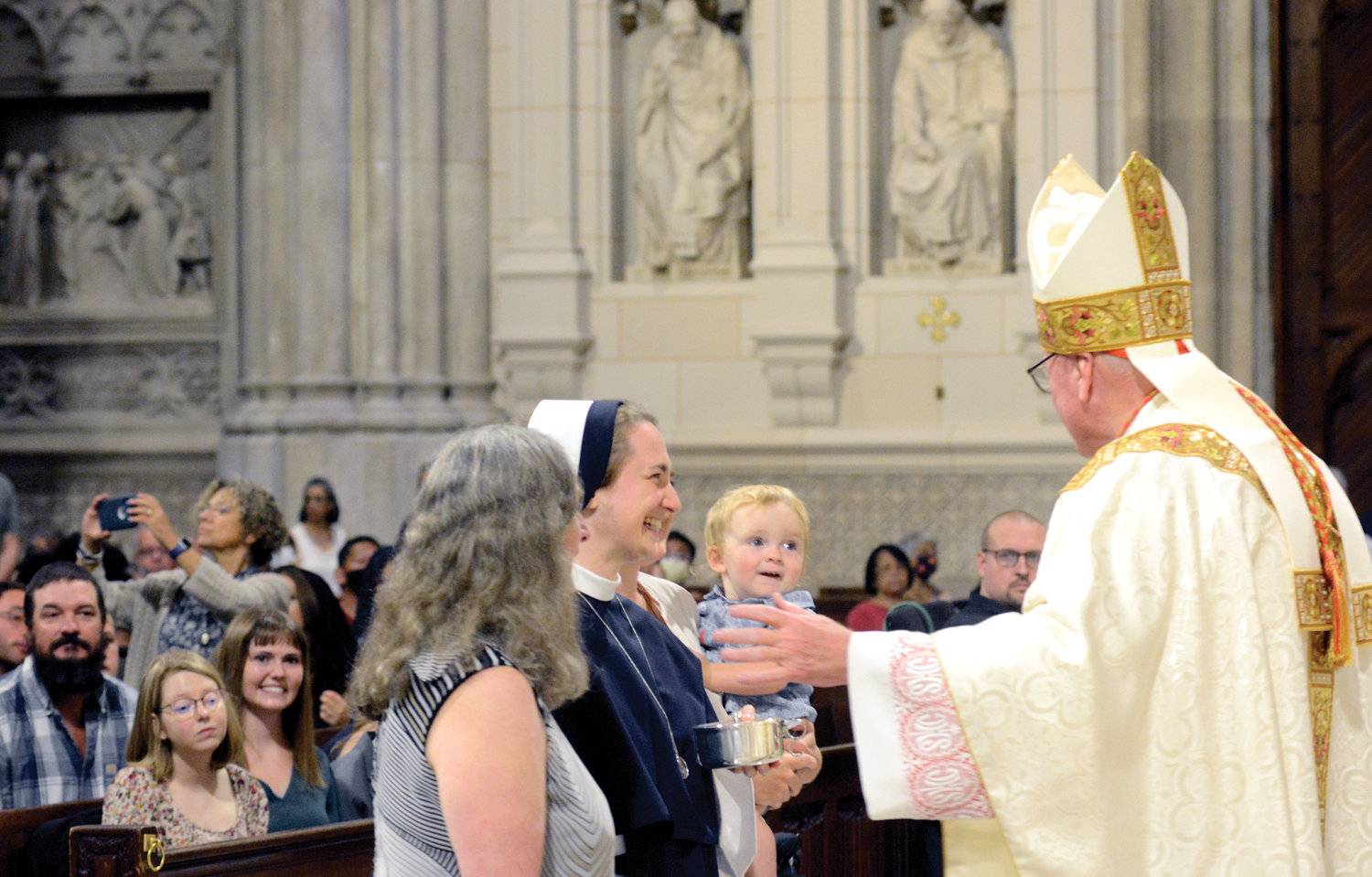 Cardinal Dolan celebrated Mass as six Sisters of Life made their final vows at St. Patrick’s Cathedral Aug. 6. The cardinal accepts offertory gifts from Sister Cara Marie, S.V., and her family members.