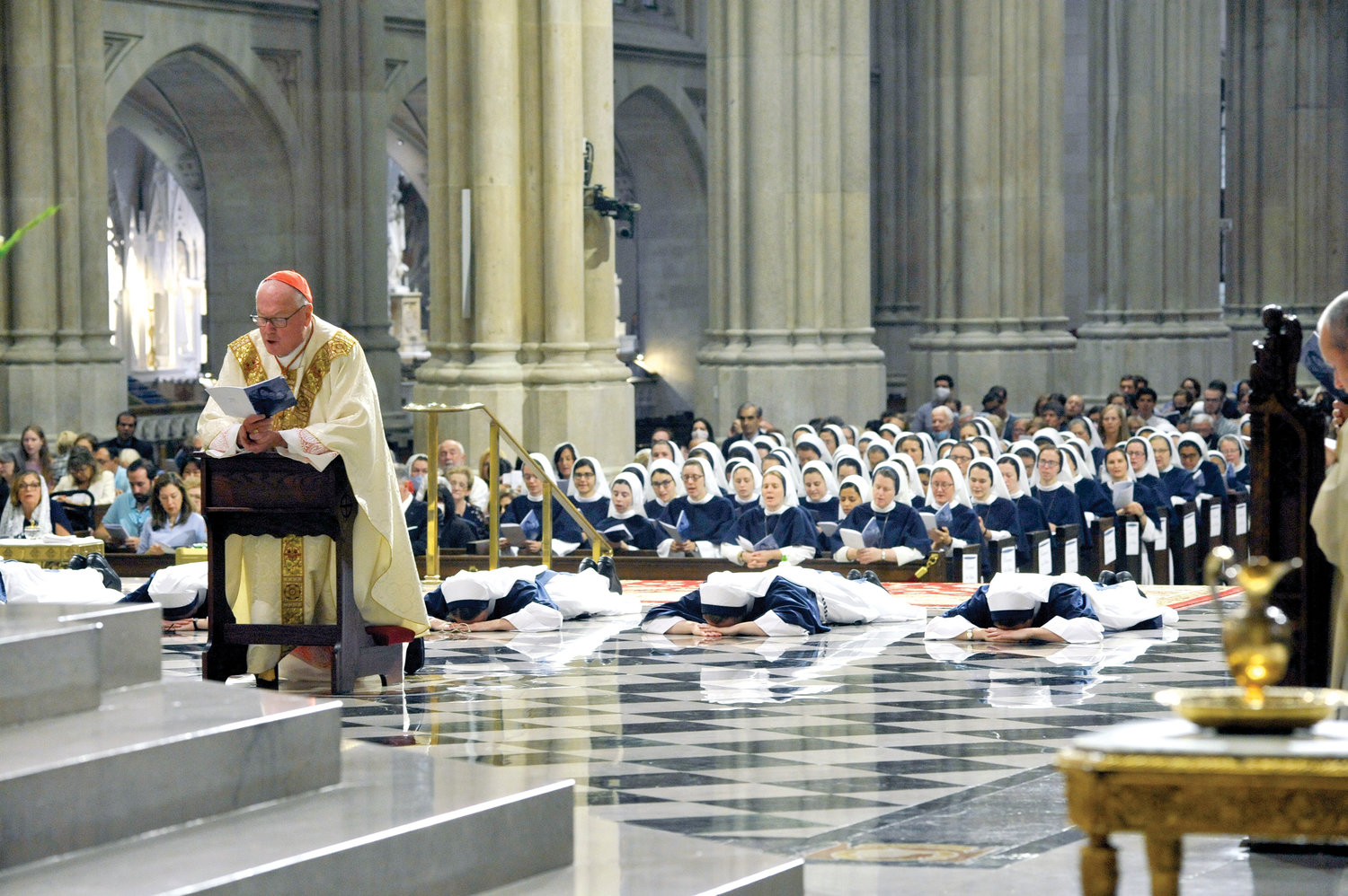 Cardinal Dolan celebrated Mass as six Sisters of Life made their final vows at St. Patrick’s Cathedral Aug. 6. Cardinal Dolan kneels in prayer with the Sisters professing their vows on the floor of the sanctuary during the Litany of the Saints.