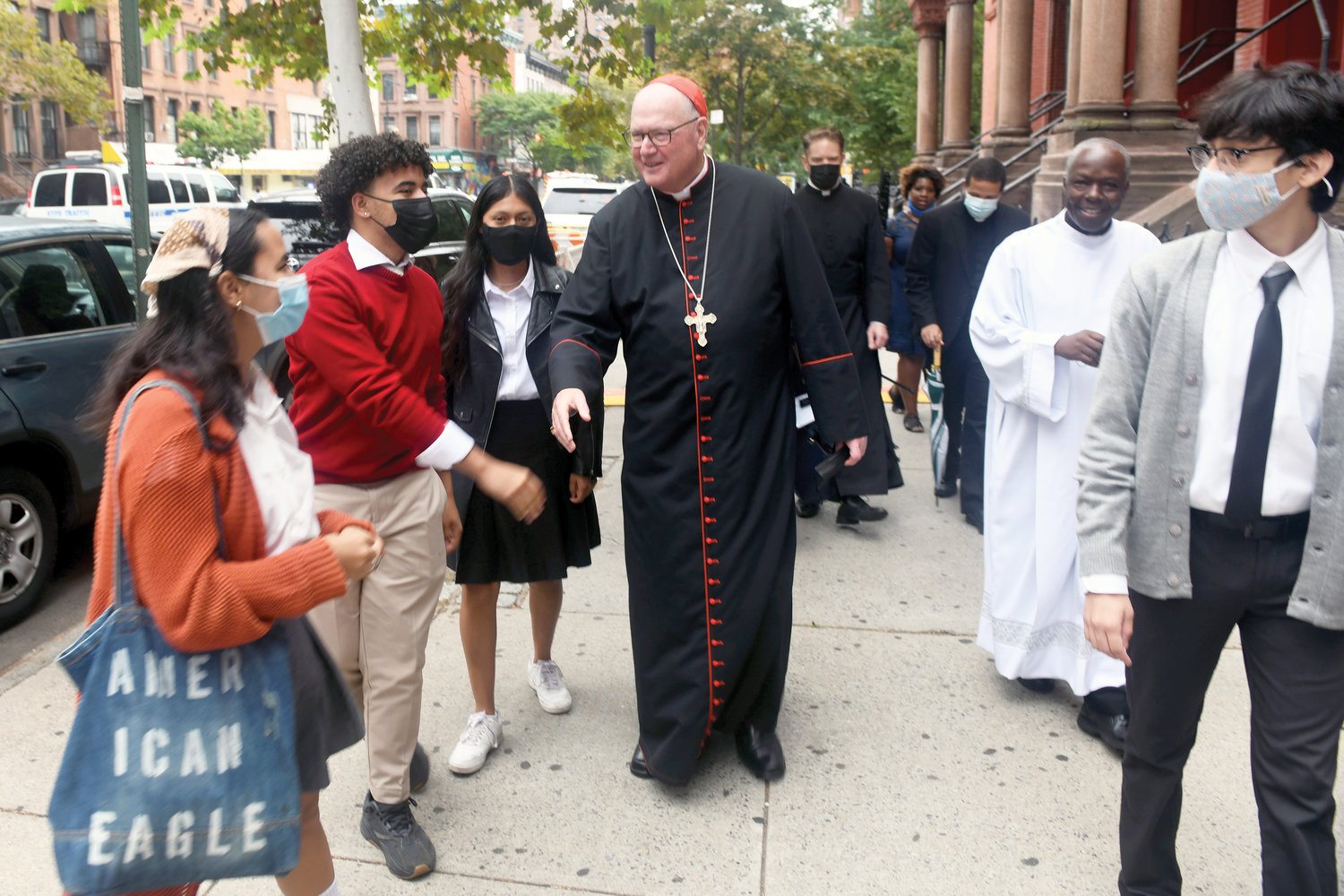 En route to tour the school after the Mass, the cardinal greets student ambassadors. Father Peter Mushi, pastor of St. Cecilia and Holy Agony, is to the right of the cardinal.