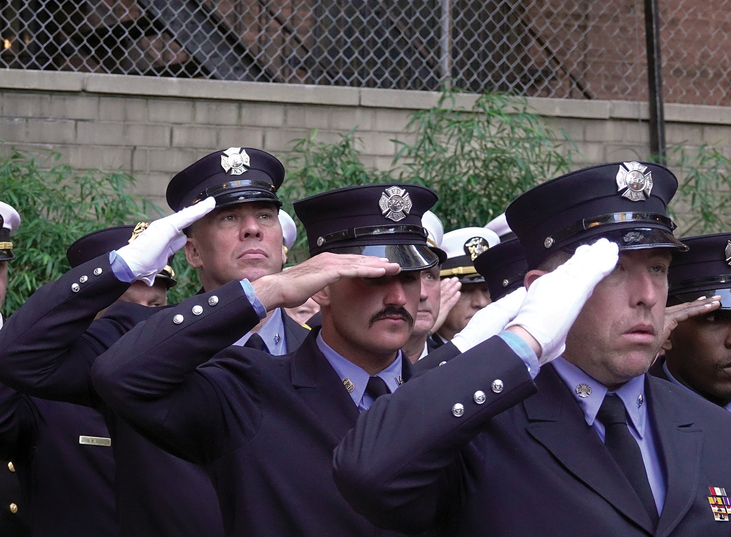Firefighters offer a salute during the outdoor memorial service Sept. 11 at Firefighters Memorial Park in Manhattan. Cardinal Dolan administered a blessing.