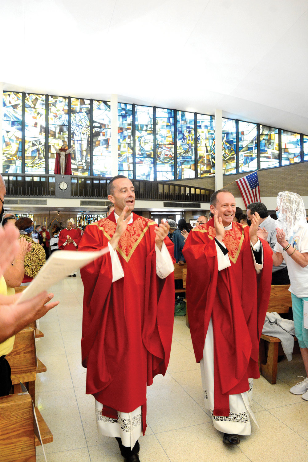Father Vincent Druding, parochial vicar, left, and Father John Higgins, pastor, show their joy during the opening procession of the 100th anniversary Mass at Holy Cross Church in the Bronx Sept. 19.