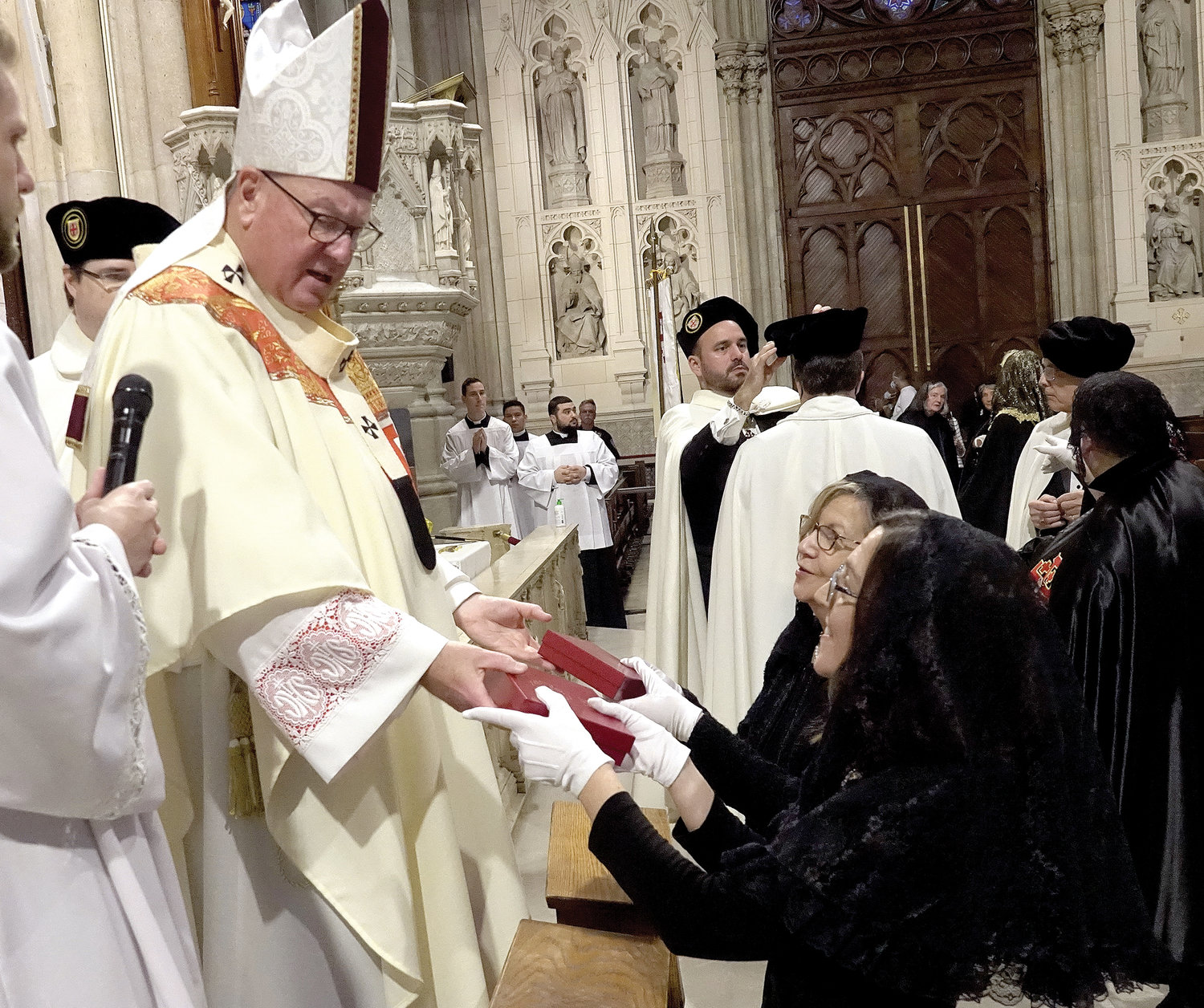 WELCOME—Cardinal Dolan offers congratulations and makes a presentation to two newly invested dames of the Equestrian Order of the Holy Sepulchre of Jesusalem’s Eastern Lieutenancy of the United States at a ceremony and Mass at St. Patrick’s Cathedral Oct. 16.