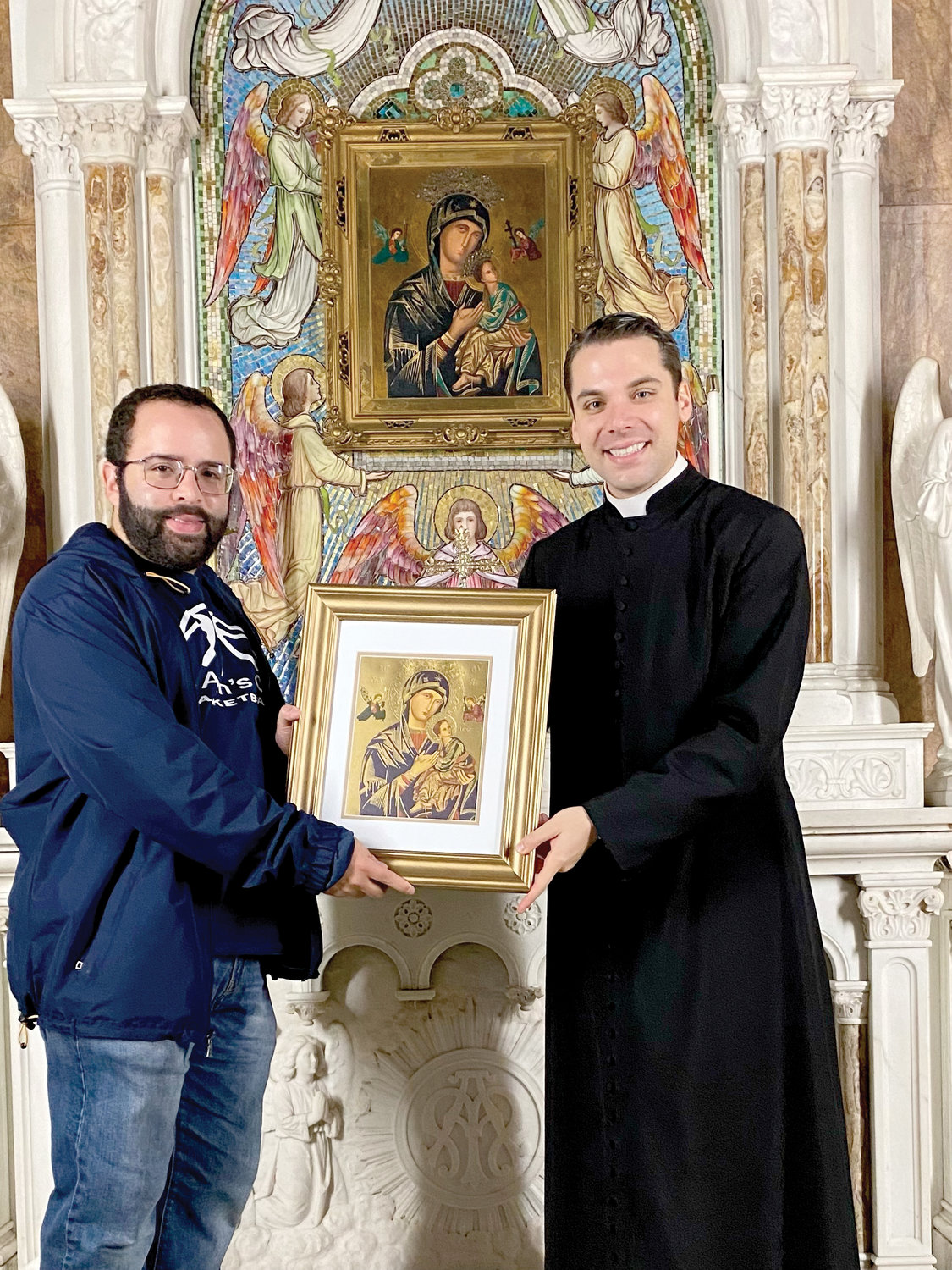 Father Seán Connolly, the administrator of Most Holy Redeemer-Nativity, presents an image of Our Mother of Perpetual Help to Father Rivera as a remembrance of his pilgrimage.