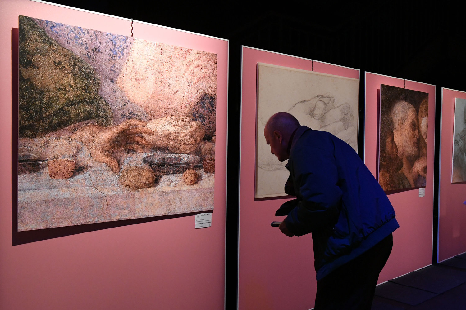 A man closely examines one of the works.