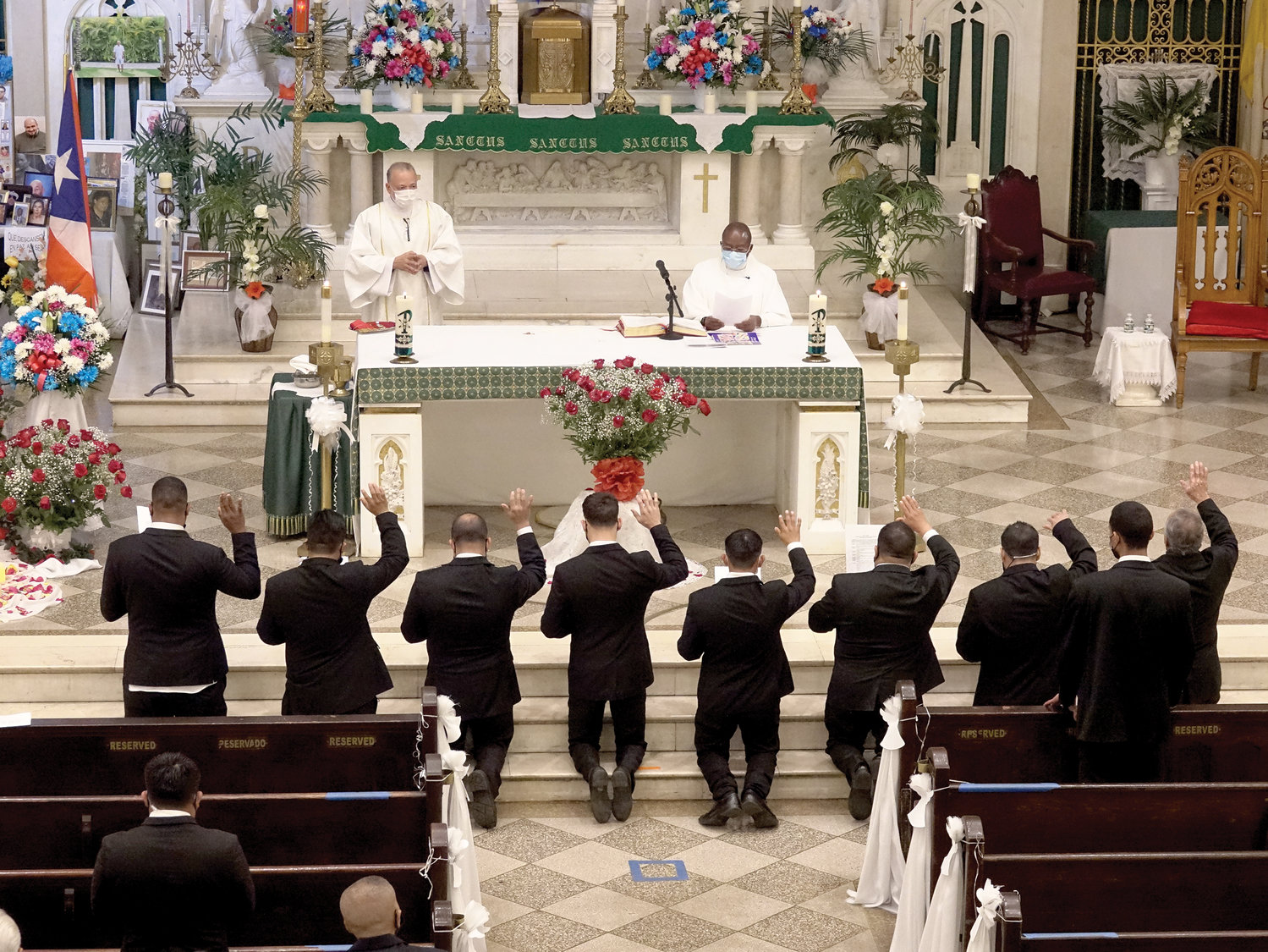 New members kneel in front of the altar as they are inducted into the Holy Name Society at the conclusion of the Mass.