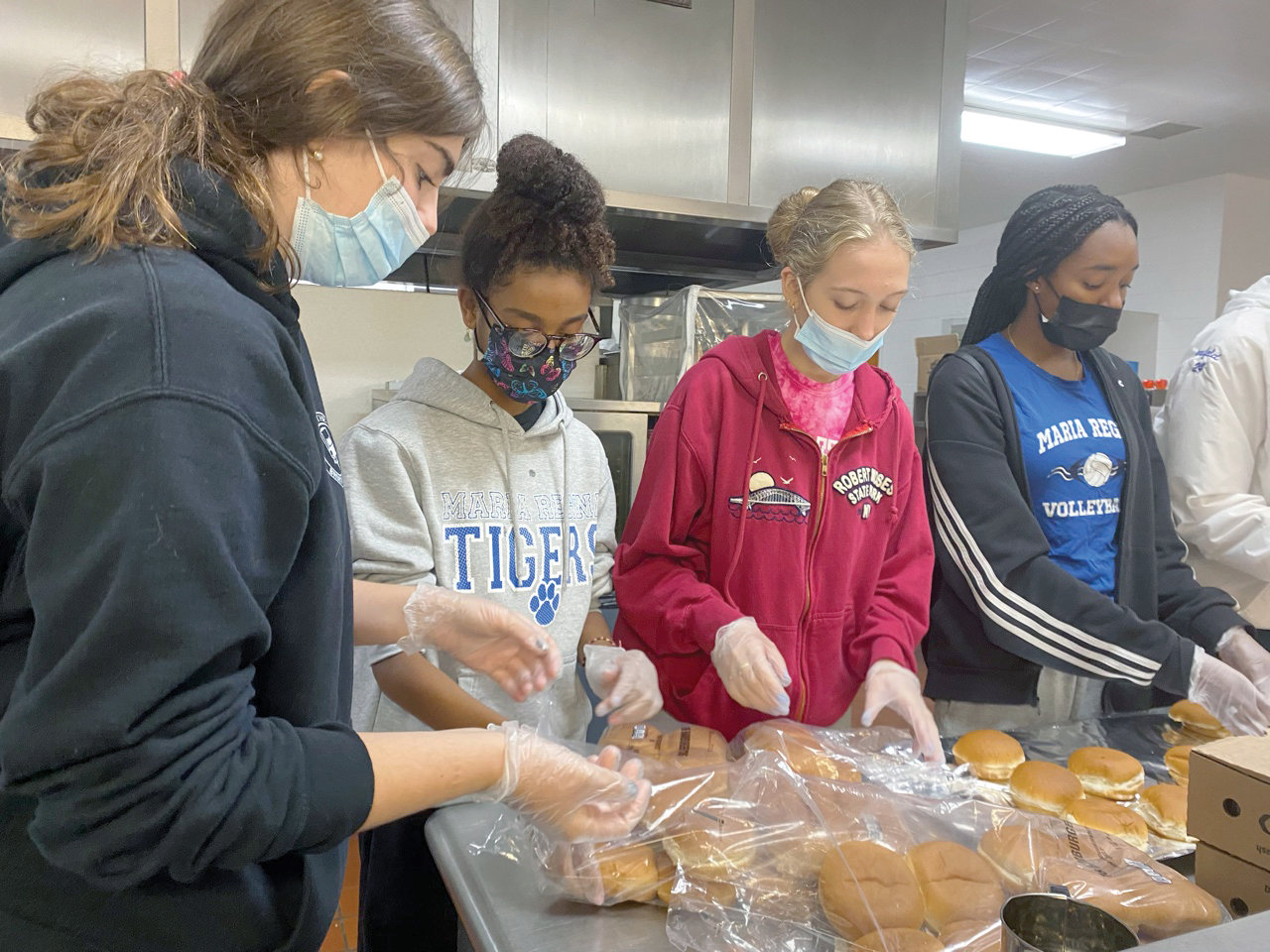 Four CRS Club members of Maria Regina High School in Hartsdale are shown preparing meals in the kitchen of the high school dining hall which were later distributed to the homeless in Manhattan as part of the school’s Breakfast Run program. They are, from left, Sophia Conroy, Jordyn Bryant, Hailey Manzo and Cyanna Shirley.