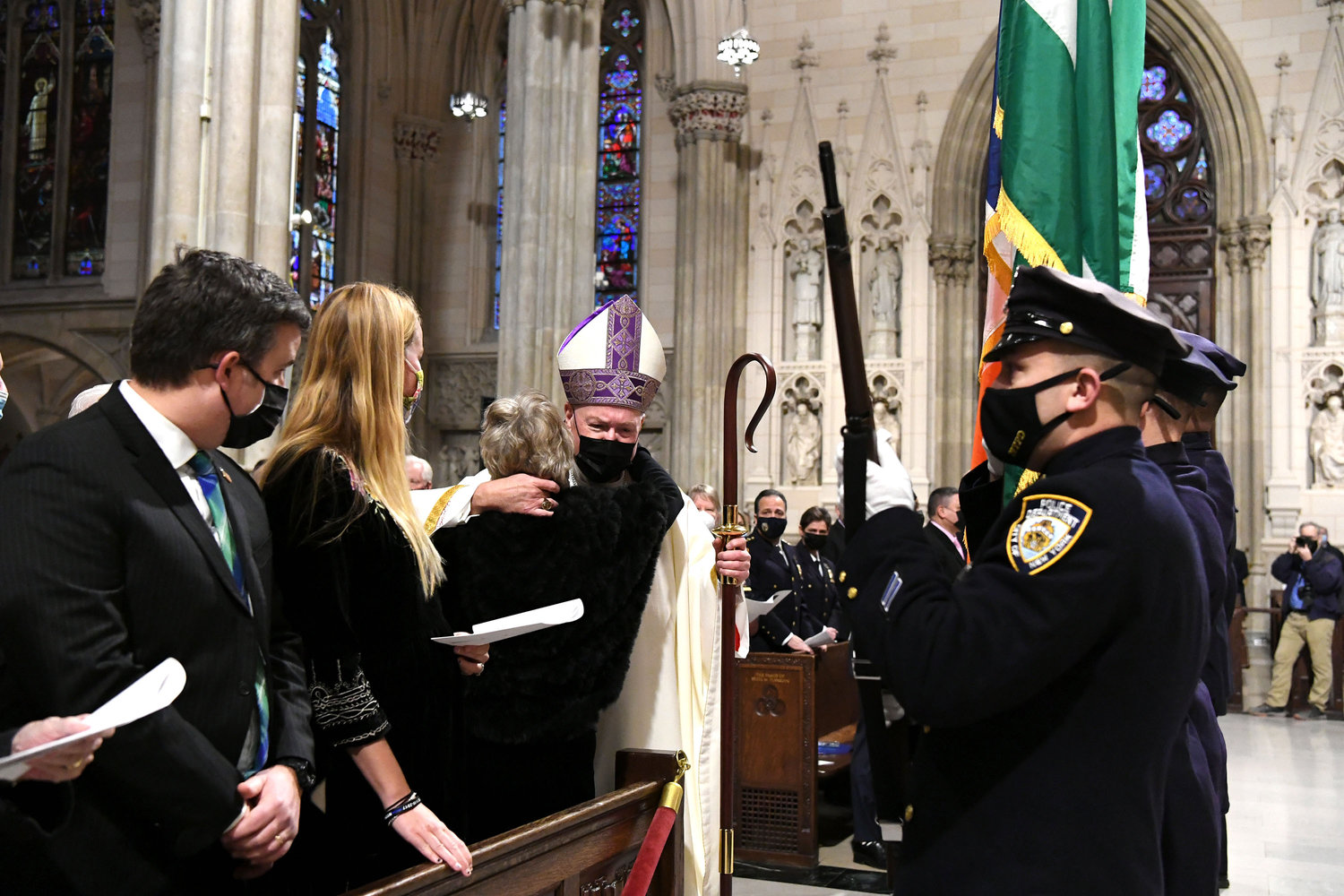Cardinal Dolan greets Patti Ann McDonald, widow of NYPD Det. Steven McDonald, during the procession at the Memorial Mass for the late detective Jan. 18 at St. Patrick’s Cathedral. Also in the pew are son Conor McDonald, far left, and his wife, Katie.