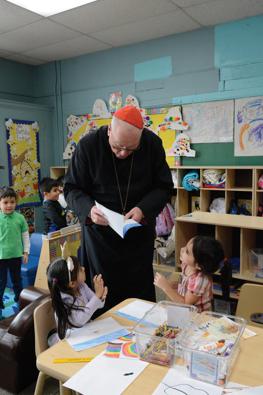 CHECKING THEIR WORK—Cardinal Dolan reviews the artwork of young students at Corpus Christi-Holy Rosary School in Port Chester during National Catholic Schools Week in January 2020. The cardinal was present for a ceremony celebrating the school’s new universal pre-kindergarten program.