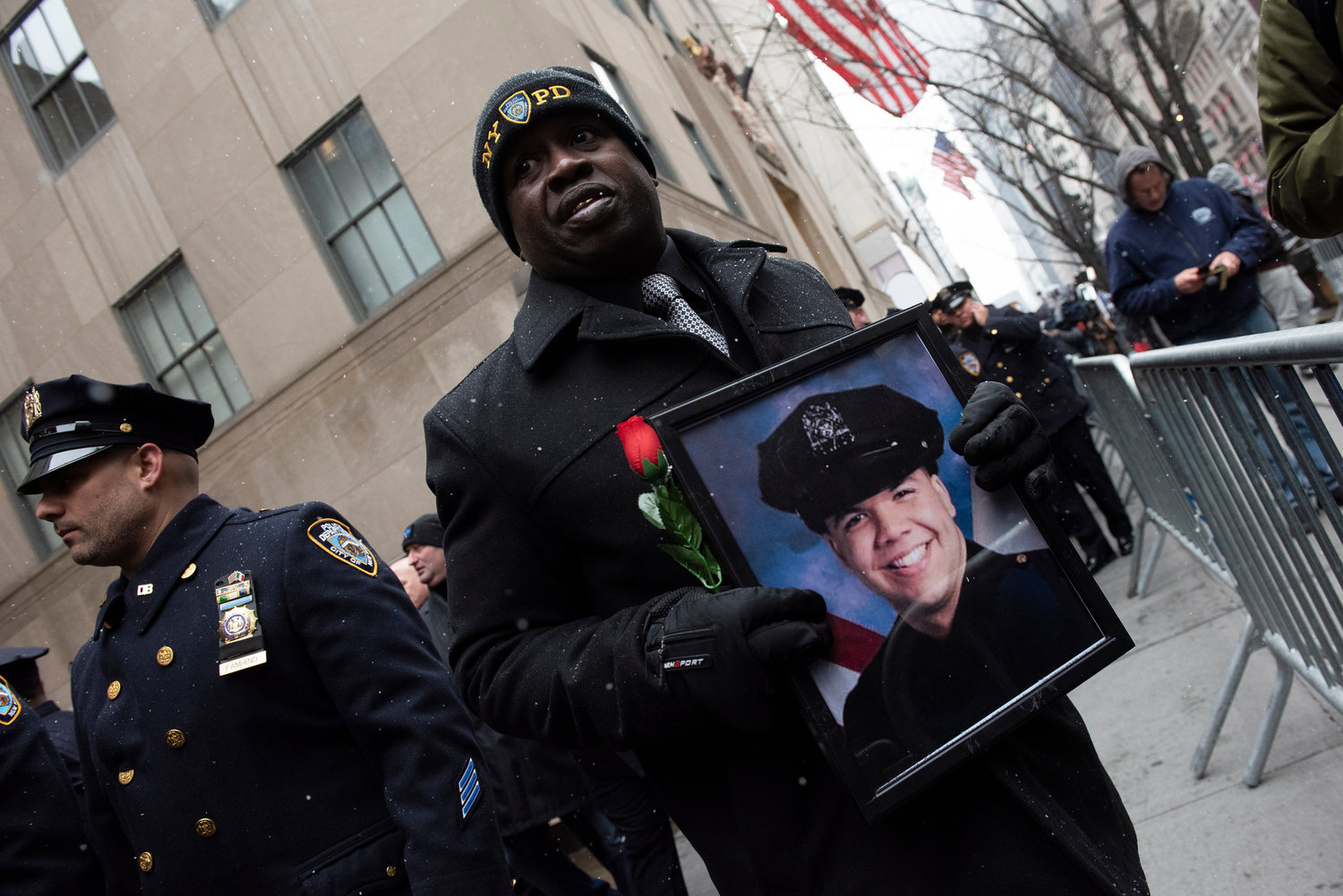 NYPD representative holds a framed portrait of a beaming Rivera in his NYPD uniform.