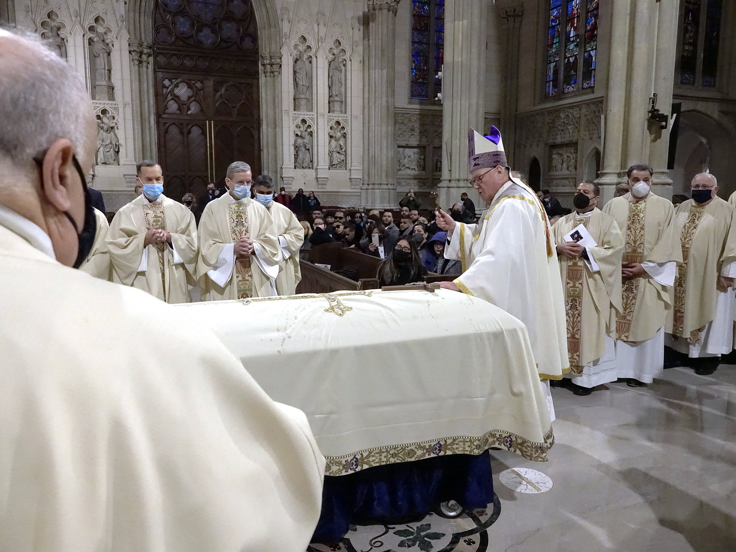 Cardinal Dolan sprinkles holy water on the casket.
