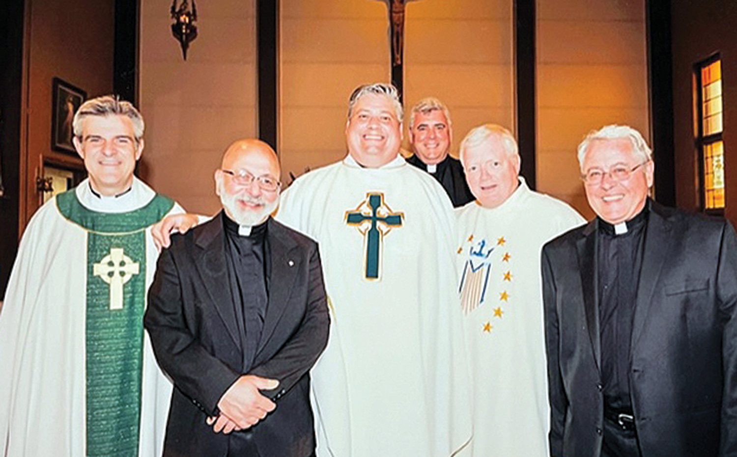 The fraternity of the priesthood is evident as various priest friends surround Father Bonnici.