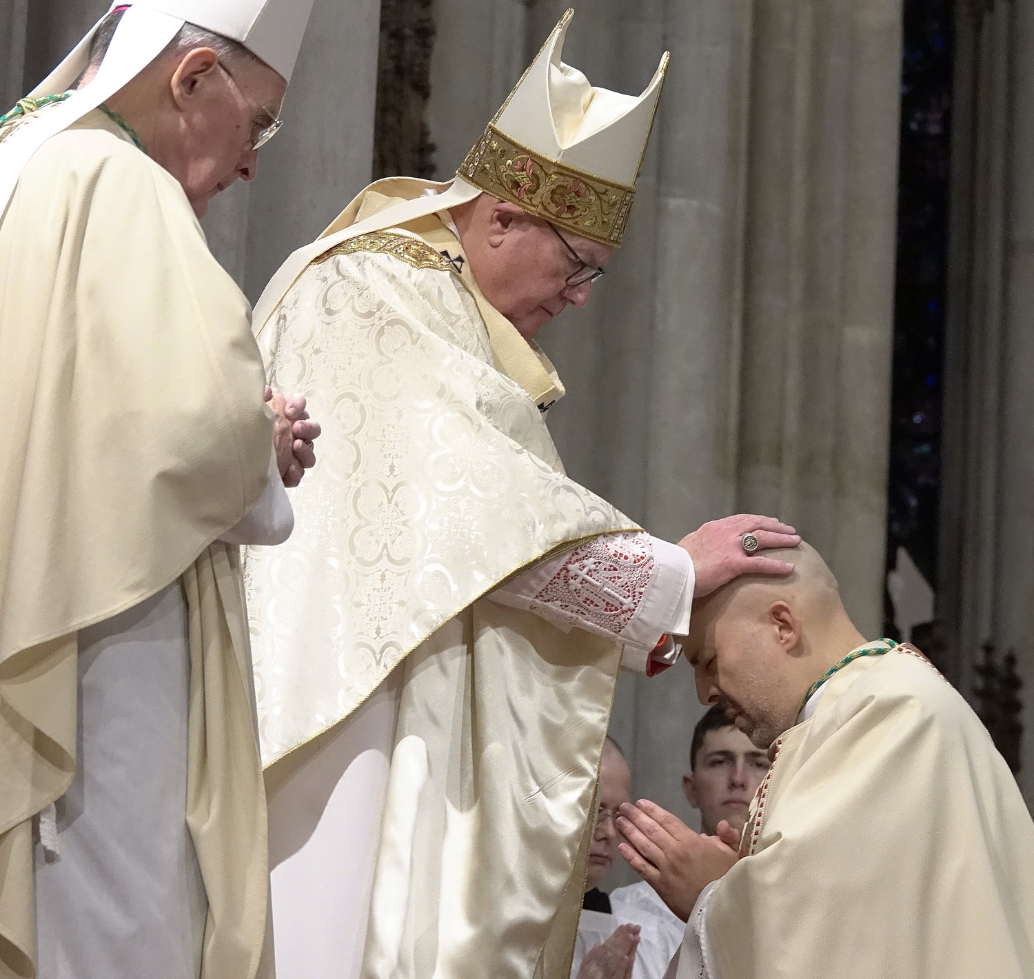 Cardinal Dolan lays hands on the head of Auxiliary Bishop Joseph A. Espaillat during his episcopal ordination March 1 at St. Patrick's Cathedral. At left is Auxiliary Bishop Emeritus Gerald T. Walsh, one of the co-ordaining bishops.