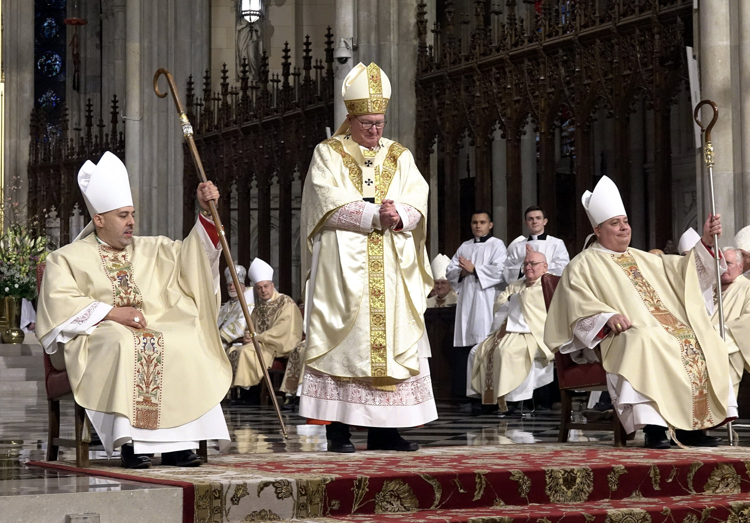 Cardinal Dolan stands between his newly ordained auxiliary bishops as both hold their new crosiers.