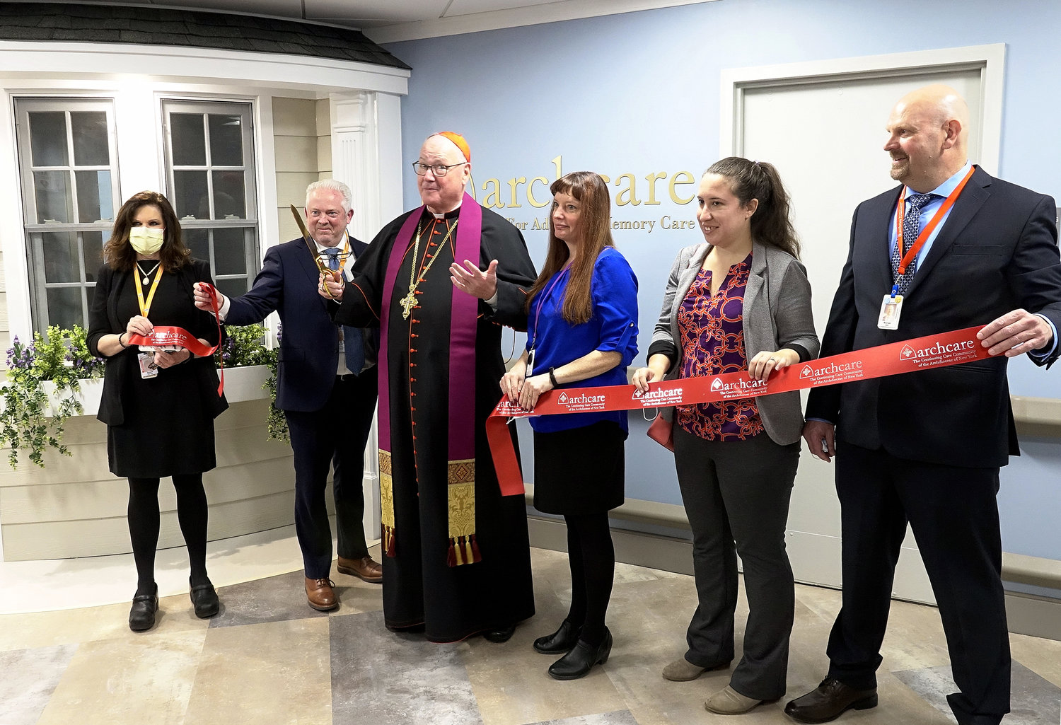 Cardinal Dolan cuts ribbon after blessing the Center for Advanced Memory Care at ArchCare at Ferncliff Nursing Home and Rehabilitation Center in Rhinebeck March 30. Participating in the ceremony, from left, are Sandy Perrotta, chief clinical officer of ArchCare at Ferncliff; Scott LaRue, president and CEO of ArchCare; Cardinal Dolan; Michelle Feller, program director of Center for Advanced Memory Care; Maria Scigliano, program and grants officer at Mother Cabrini Health Foundation; and Michael Deyo, executive director of ArchCare at Ferncliff.