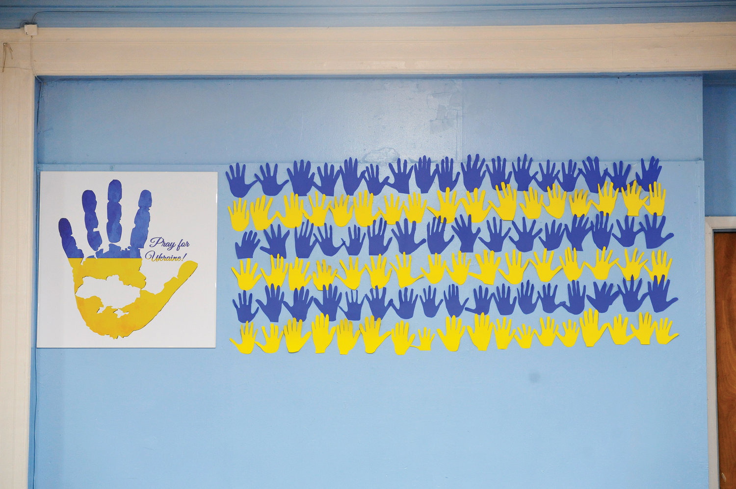 A bright mural crafted by students depicts handprints and hope, and bears the blue and yellow colors of the Ukraine flag.