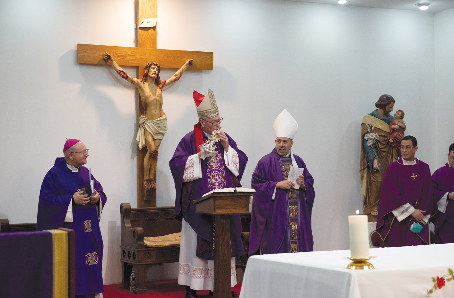 El cardenal Dolan besa un relicario. El arzobispo Doménico Sorrentino de Asís, izquierda, y el obispo auxiliar Joseph Espaillat, obispo episcopal del Bronx, están con el cardenal.