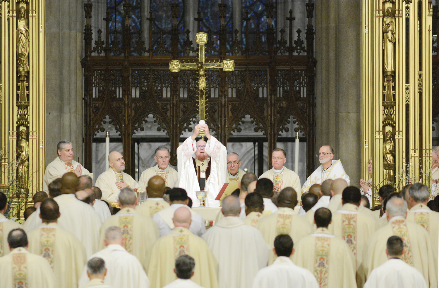 Cardinal Dolan elevates the Eucharist during the Chrism Mass April 12 as bishops and priests fill the sanctuary of St. Patrick’s Cathedral.